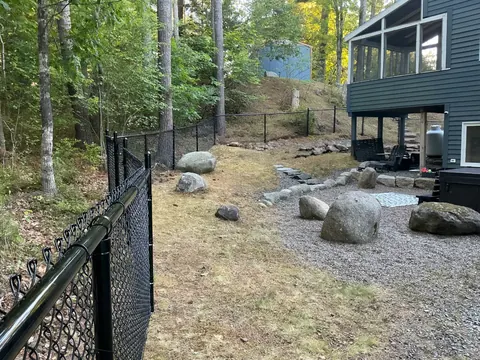 Black chain-link fence project around a wooded yard